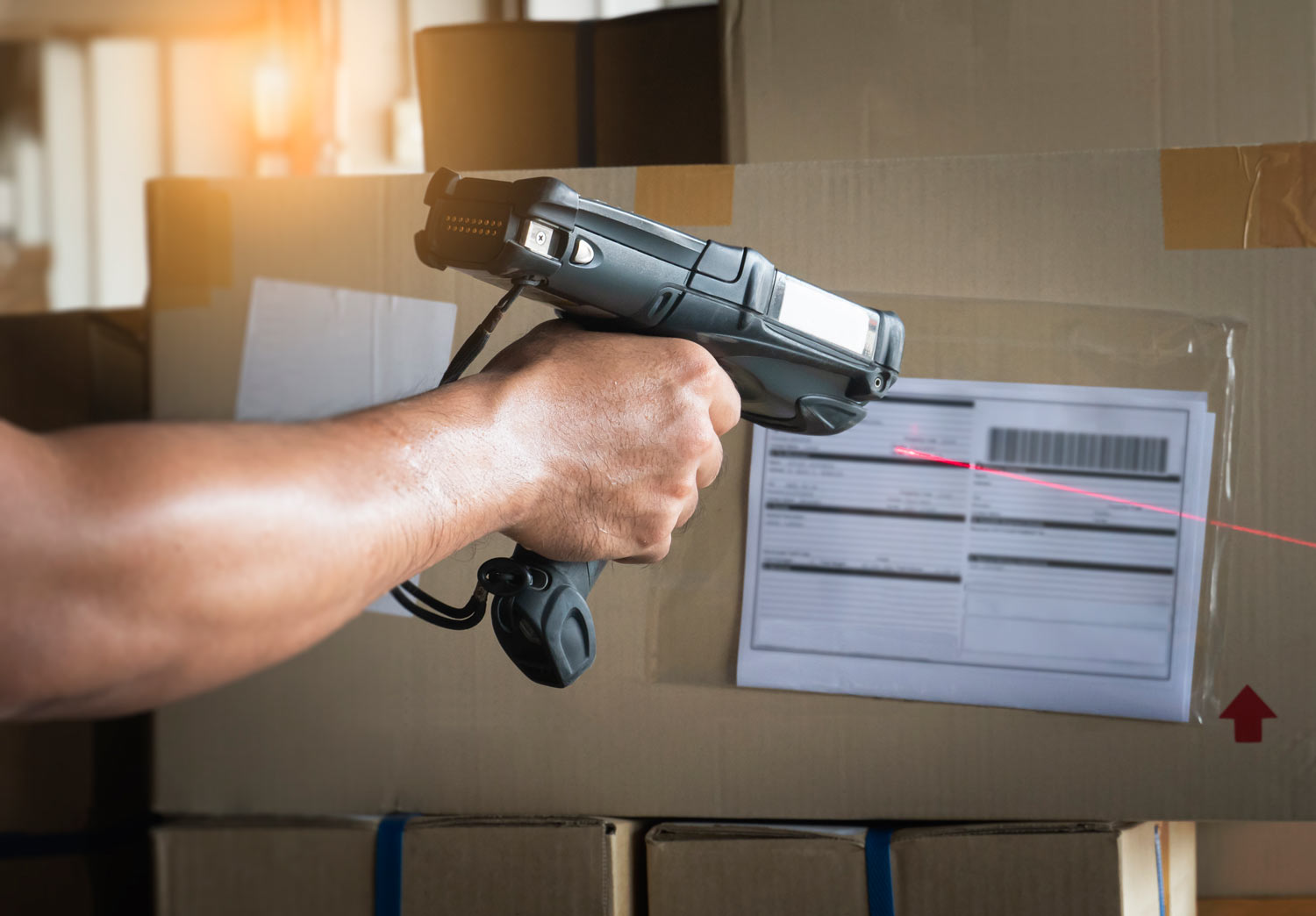Mitarbeiter scannt Barcodes auf Paketen im Lager eines Unternehmens